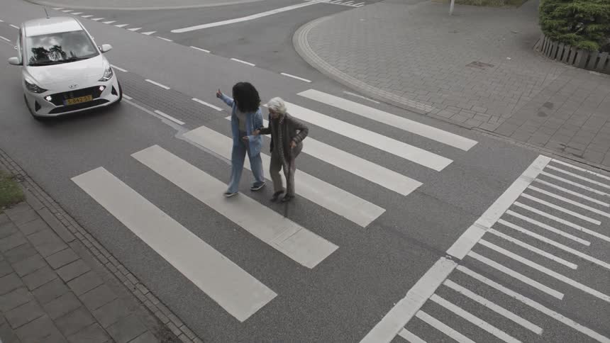 A clip of a lady and and an elderly woman crossing the road