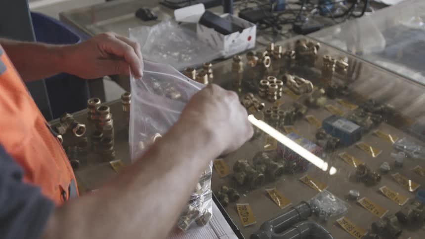 A worker is filling a baggie with pipe fittings