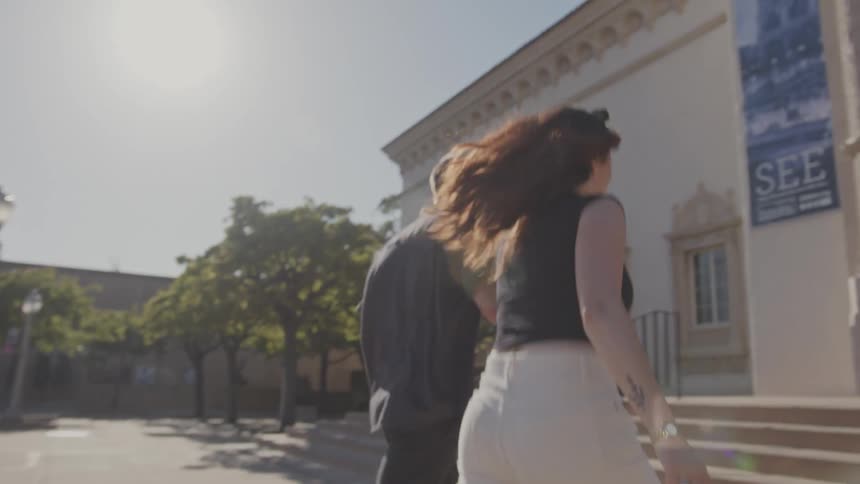Couple holding hands and walking up the stairs together towards a historical museum