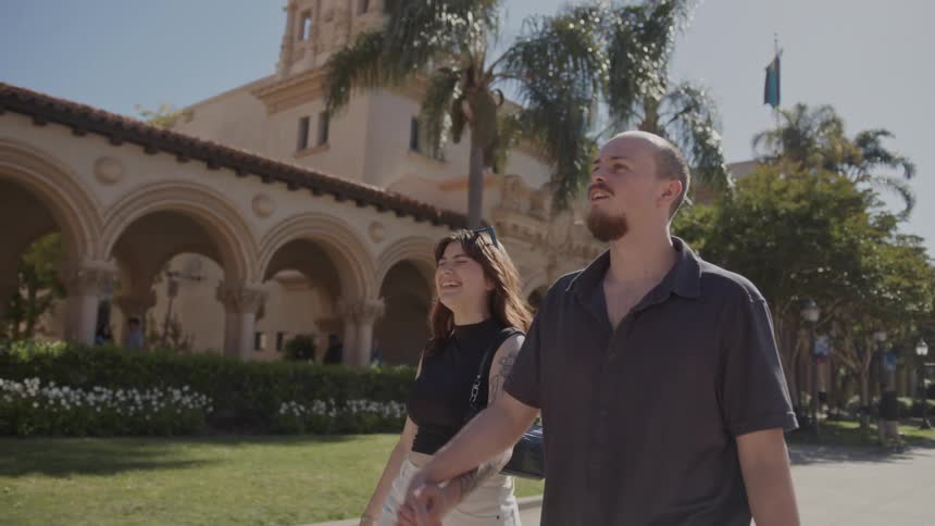A couple of tourists walk hand in hand outside balboa park