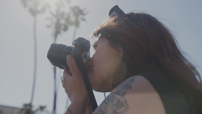 Woman takes a picture outdoors on a sunny day then shows image to man