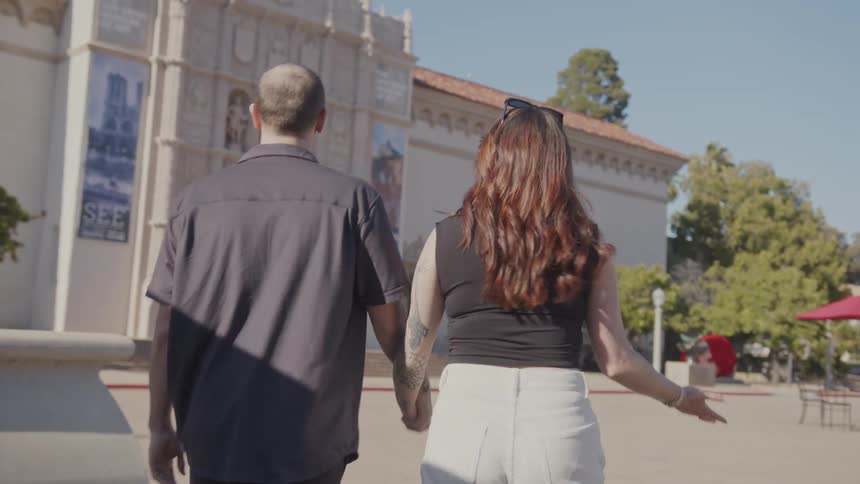 Couple walks across plaza passing outdoor tables on the way to a museum