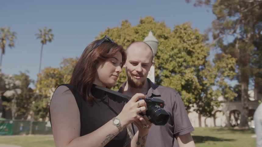 A woman captures a moment with her camera while a man gestures