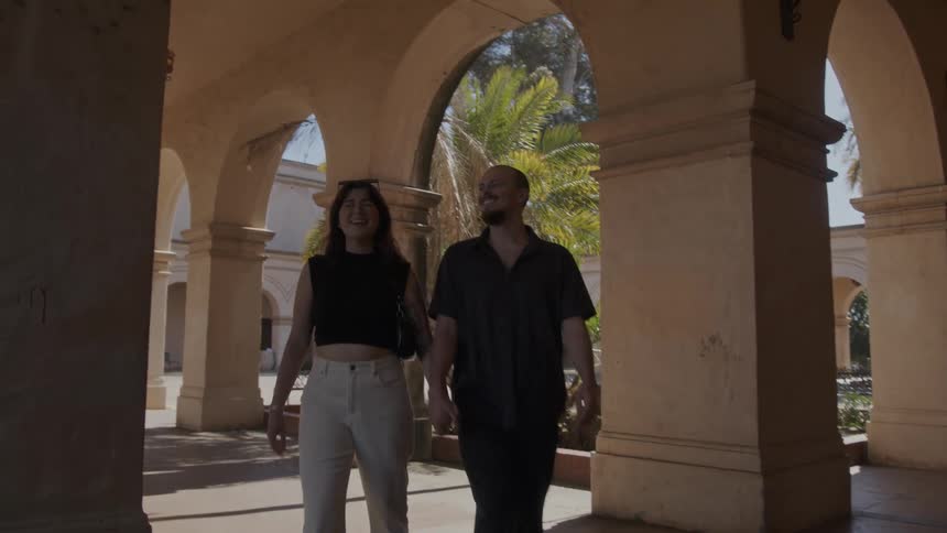 A couple walks out of a compound and heads to a street