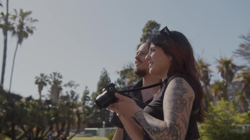 Female photographer takes picture following pointing finger of male friend