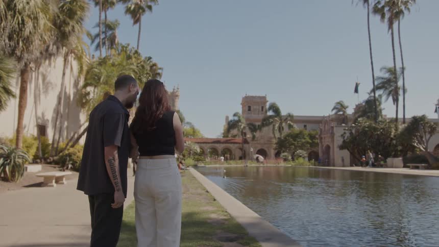 A couple take pictures of birds in a pond on a college campus
