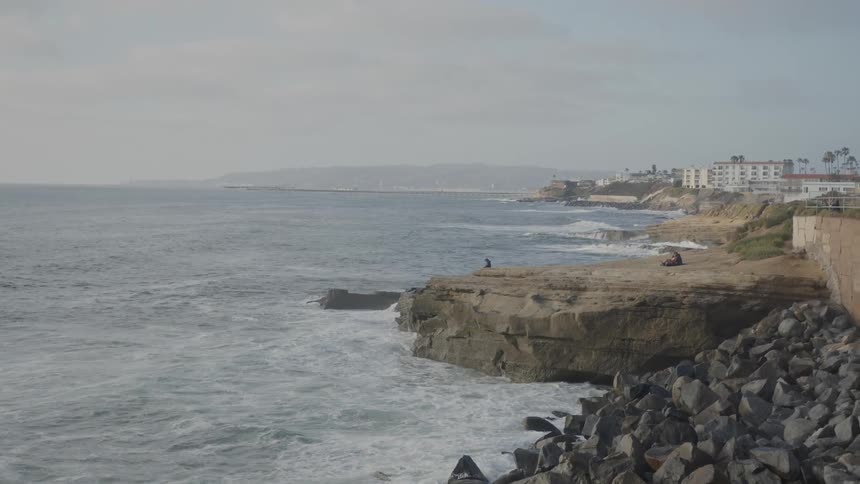 Coastal area with buildings in the background and a sea that hits the rocks