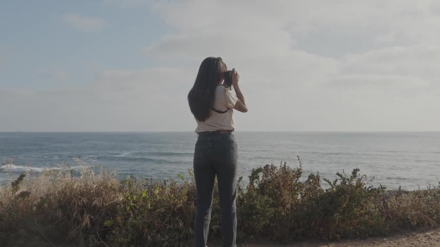 A back clip of a lady taking a photograph