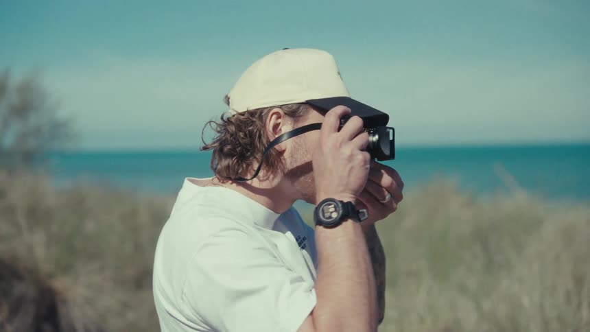 Man walking in a natural environment and using his professional camera