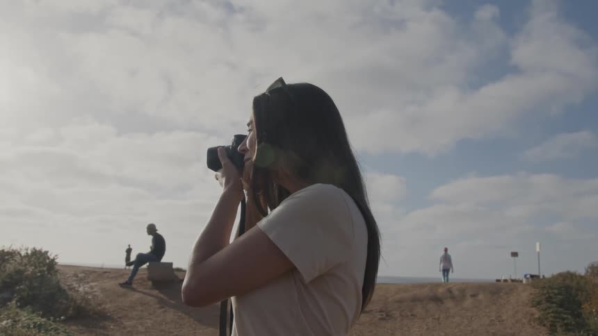 A woman takes photos on the beach