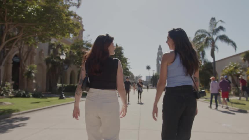 Back view of two women walking in a tourist location while talking and smiling