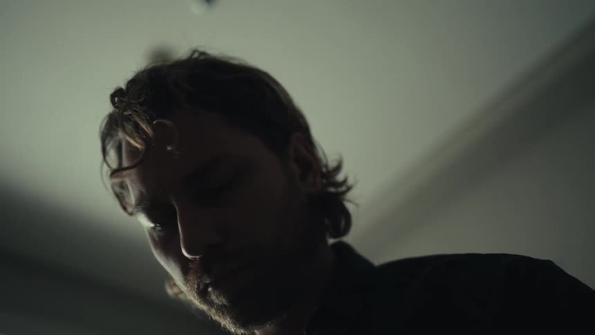A man with unruly hair looks around a room