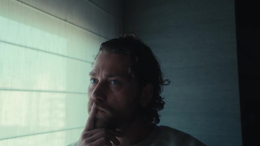 Portrait of a pensive man next to a window shutter