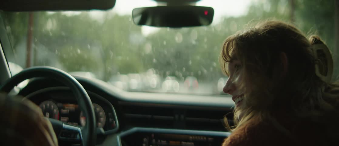 A man and woman look around while driving a car