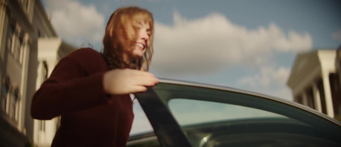 A young woman steps out of a car and shuts the door