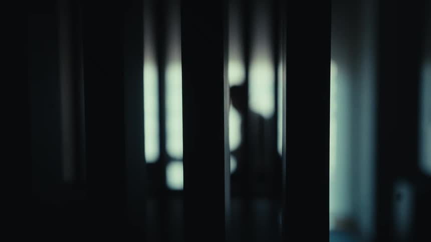 A person in silhouette moves inside a dark building