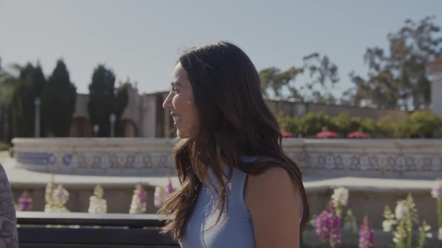 Two women sitting on a park bench talking and smiling