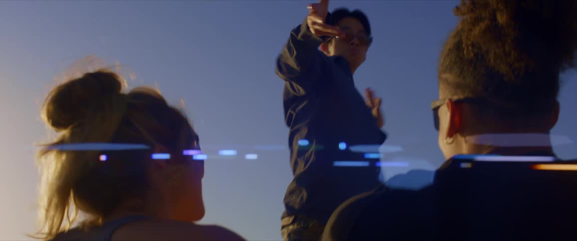 Man standing dancing and two people sitting with their hands raised enjoying together