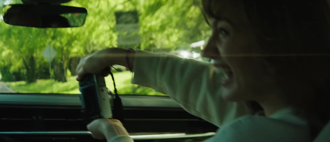 A woman in the passenger seat shows the driver her camera laughing as she does