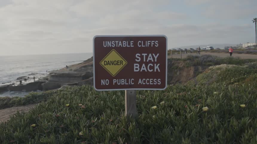 Signpost warning of danger on the seaside coast