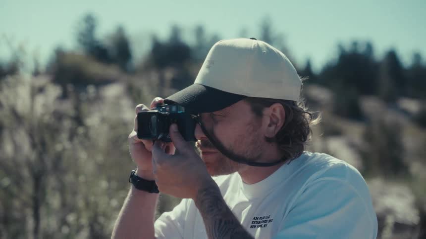 Man in a natural environment taking his professional photo camera and taking photos