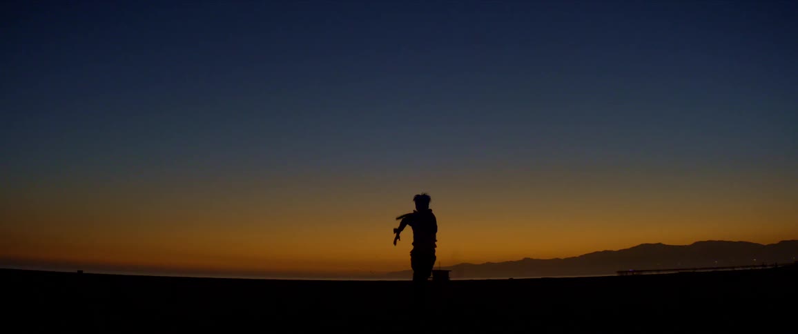A man runs across the field at sunset