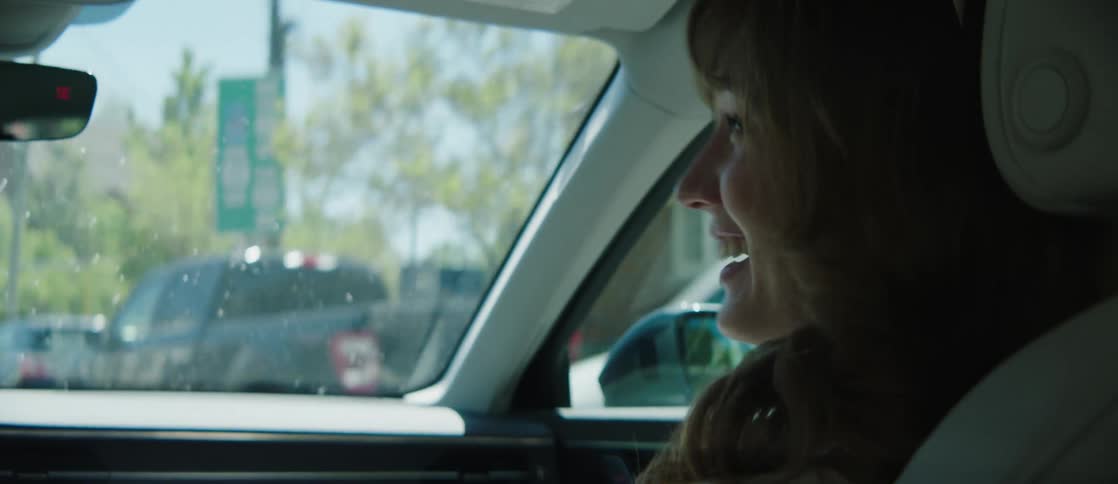 Young man and woman sitting in the front seat of a moving car talking and smiling