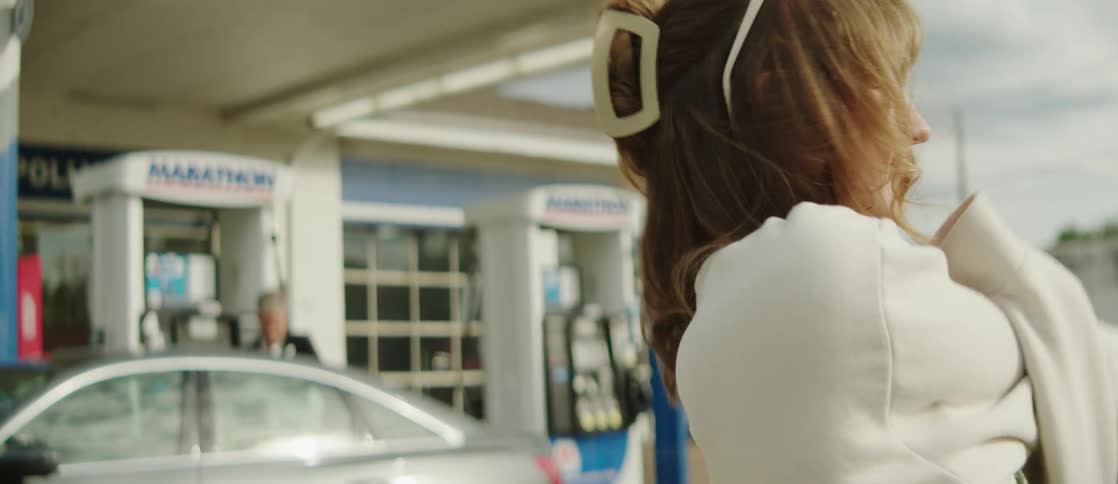 Portrait of a young woman next to a gas station stretching her arms