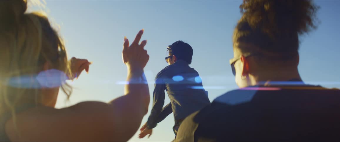 Man standing with sunglasses dancing for a couple who are sitting and enjoying the performance