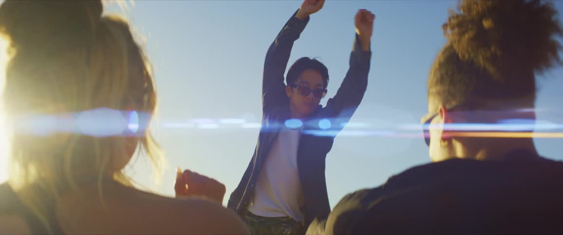 Young man standing spinning and dancing while two people sitting watch and enjoy this moment