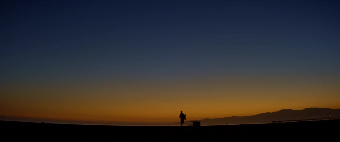 A silhouette of a person running on a beach at sunset with vibrant orange and blue sky in the background