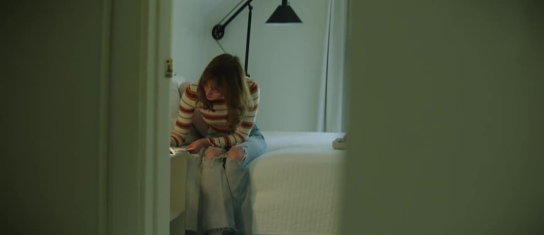 A woman sitting in the bedroom writing a handwritten note