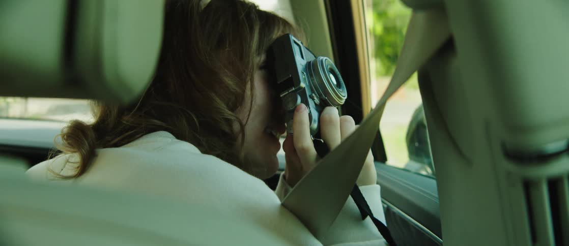 Side portrait of a young man and woman in the front seat of a vehicle photographing with a camera