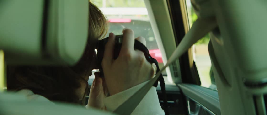 Young man and woman sitting in the front passenger seat taking photographs with a camera