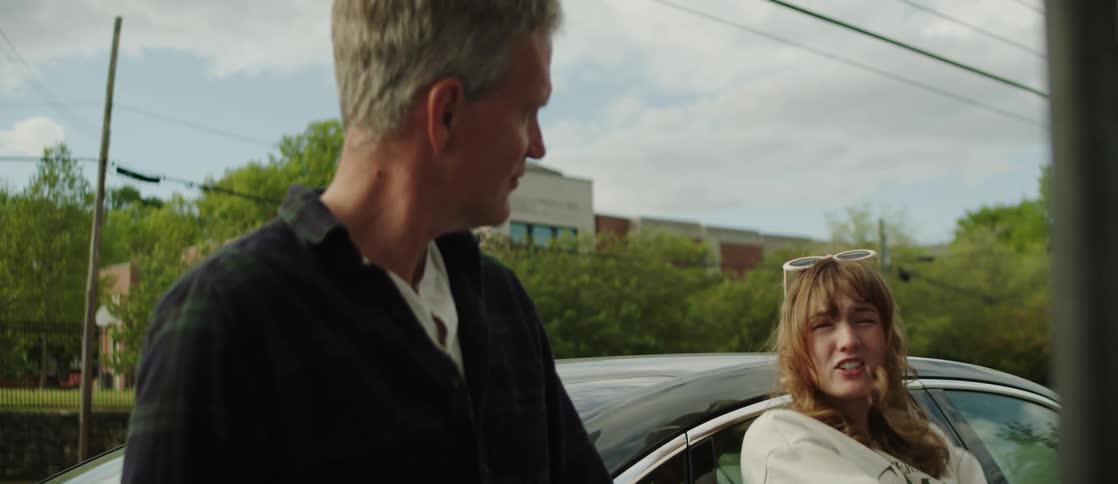 A man and woman talk near the car