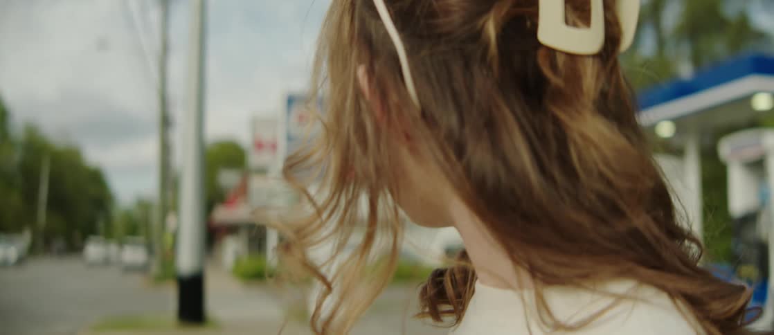 Portrait of a young woman next to a gas station and in front of a street with vehicle traffic