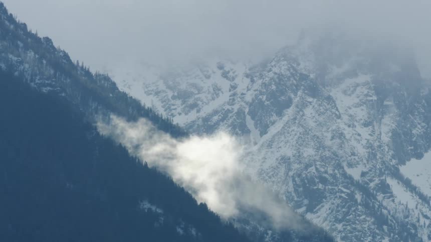 Aerial shot of clouds and snow covered mountains