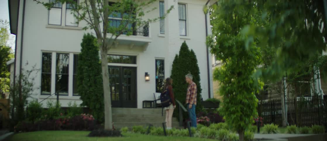 Man and woman on the sidewalk in front of a house hugging each other