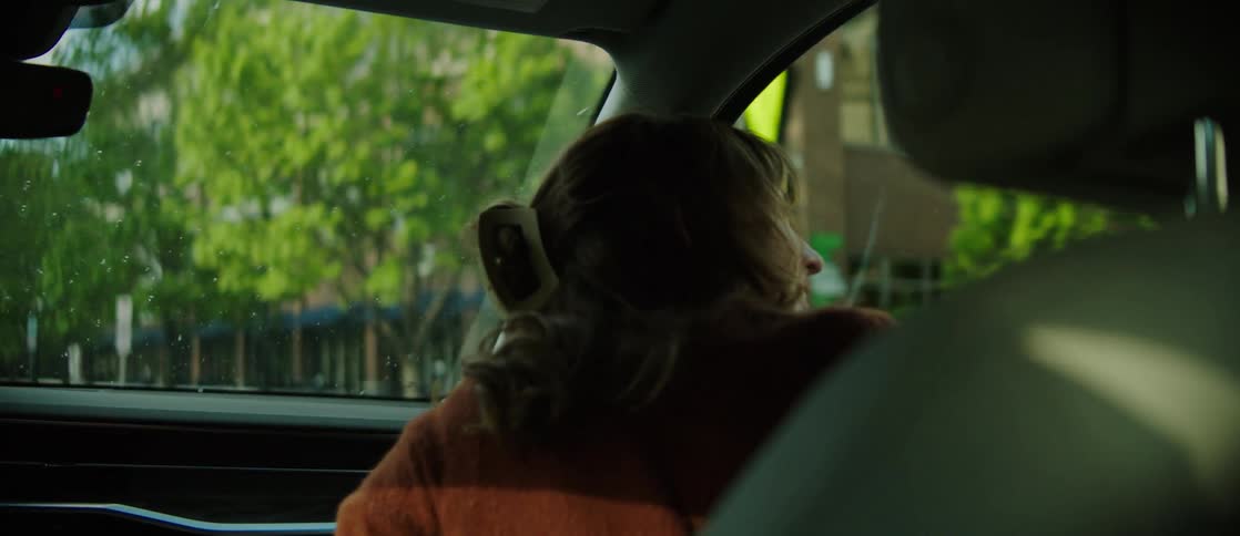 A young woman looks at campus buildings from a moving car