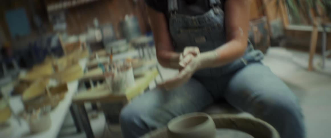 Hands of a woman with clay producing a vase manually
