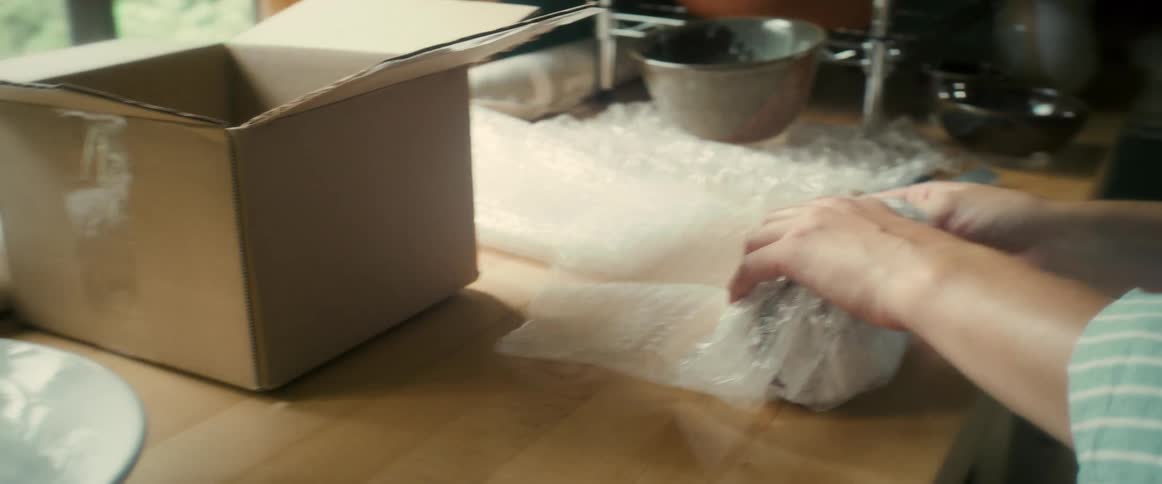 Hands carefully packing a vase in bubble wrap