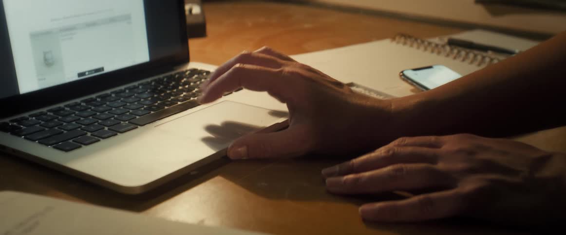 A closeup view of hands sliding on a laptop touchpad