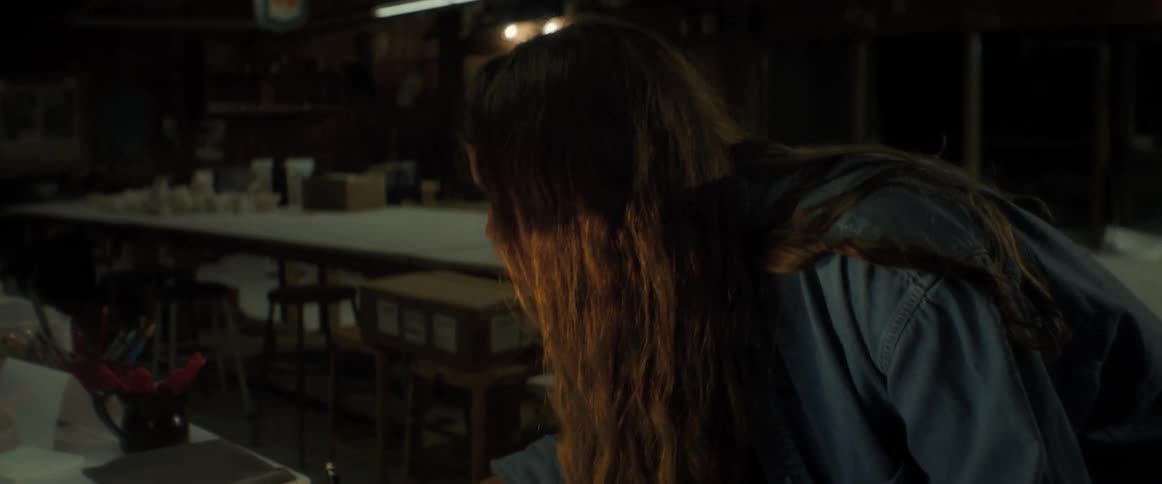 A young woman rapidly moves from a laptop to writing in a notebook