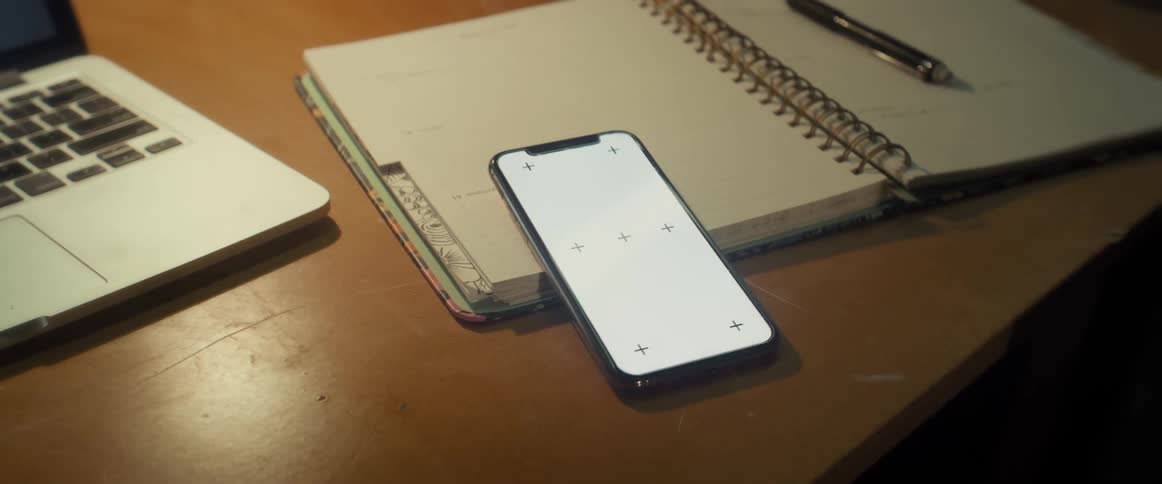 Smartphone with the screen on top of a notebook with a laptop next to it