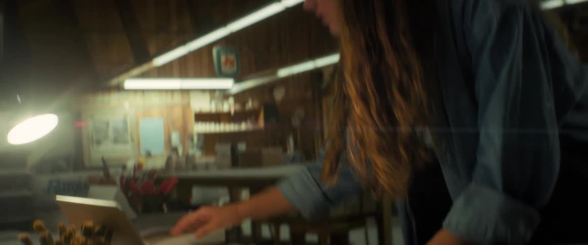 Young woman standing in front of her laptop and looking turning the pages of her notebook to the side