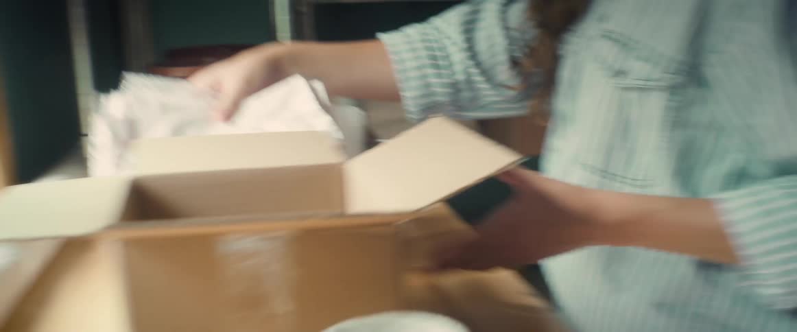 A woman prepares boxes and paper to ship a product