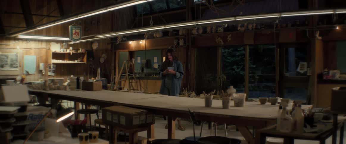 A potter paces across her workshop at night holding her phone