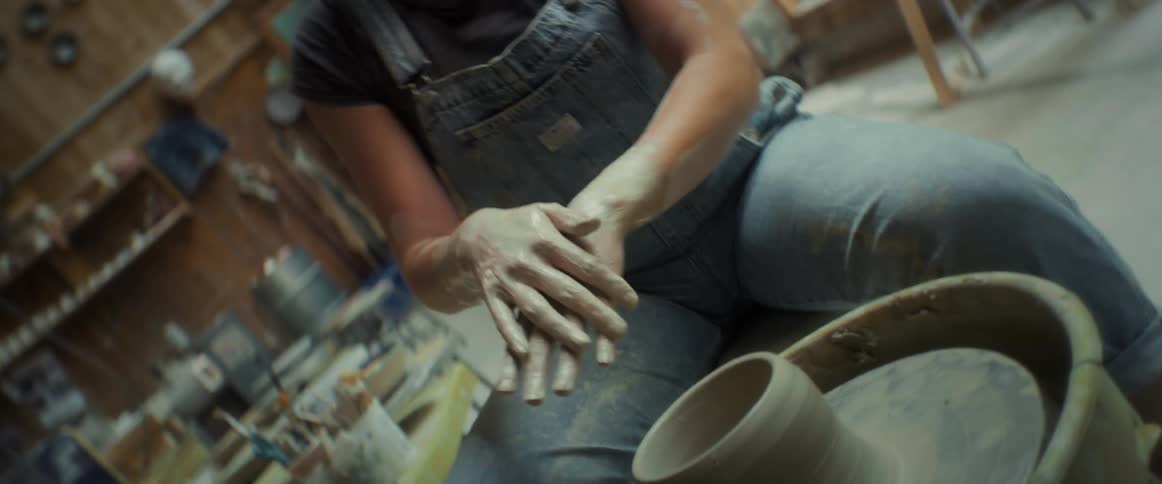 Woman sitting and passing clay on her hands