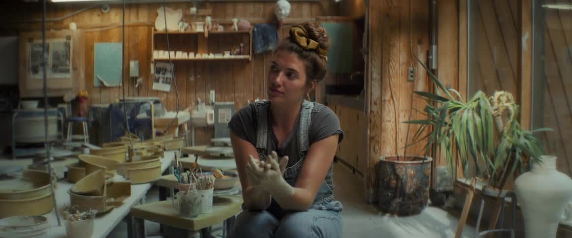 A woman rubs her hands together while sitting inside a house