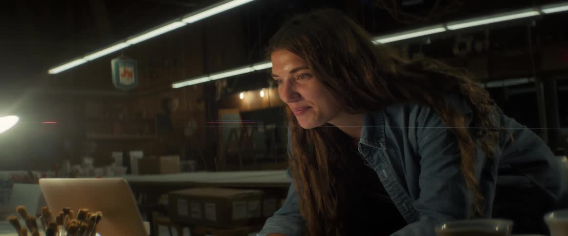 Smiling woman standing in front of a table using a laptop